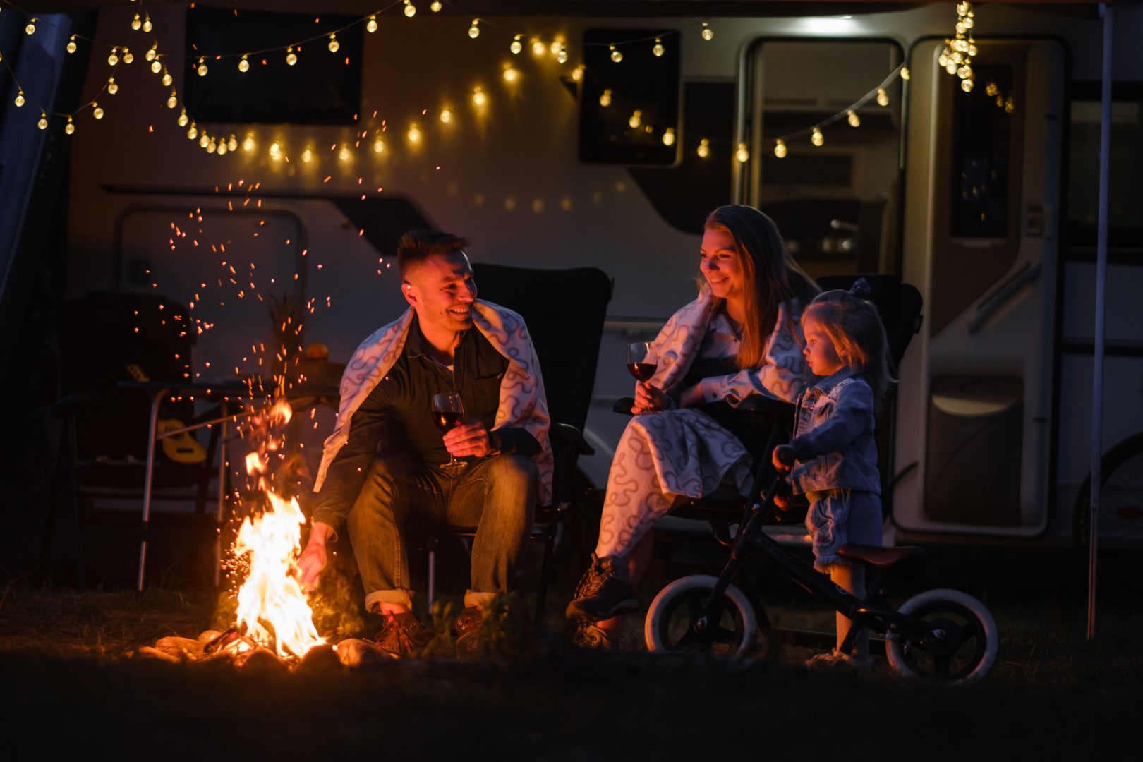 Family enjoying an evening fire at Red Rock RV Resort in Las Vegas with string lights and RV.